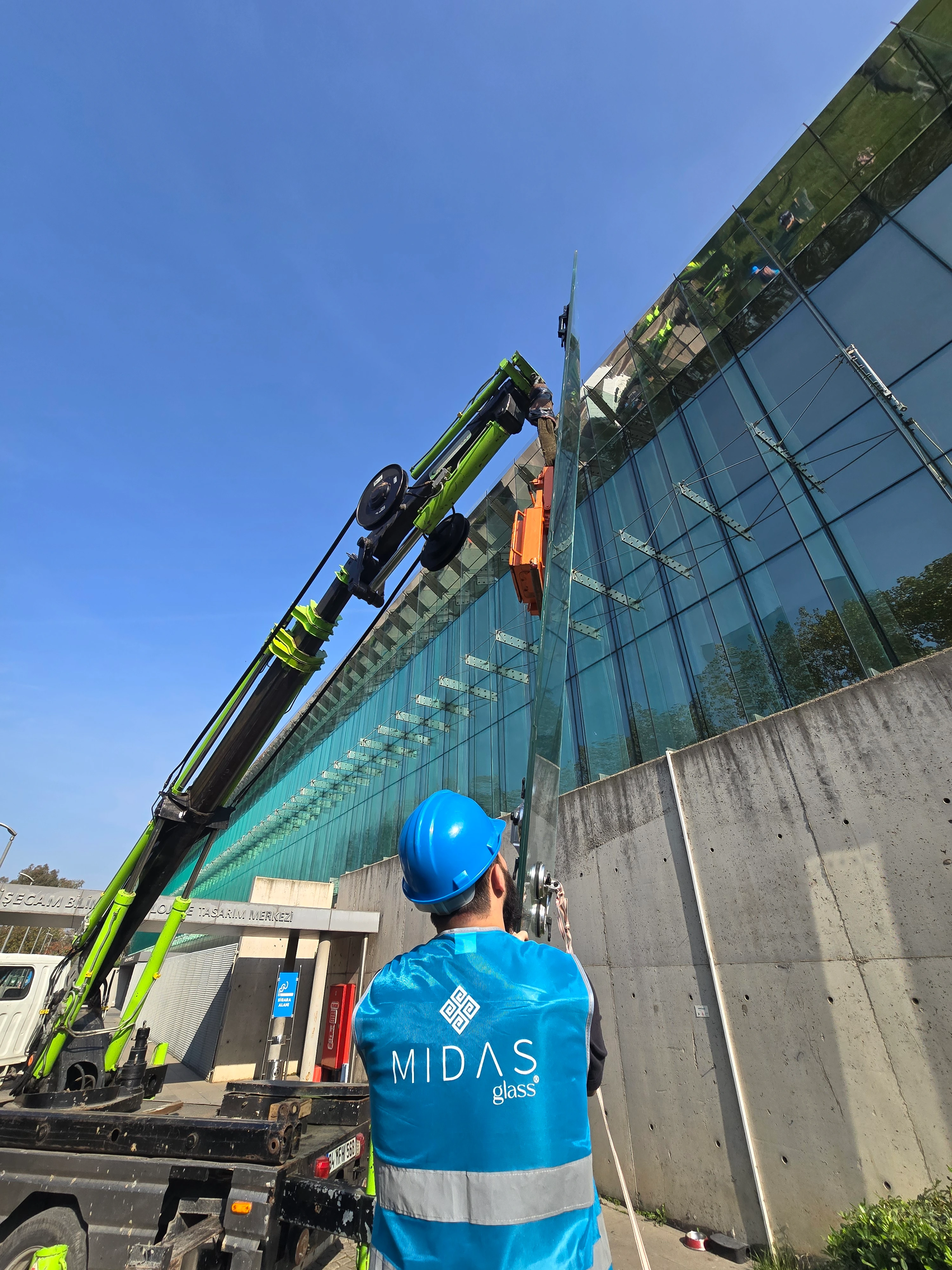 Crane lifting large glass panel for high-rise installation